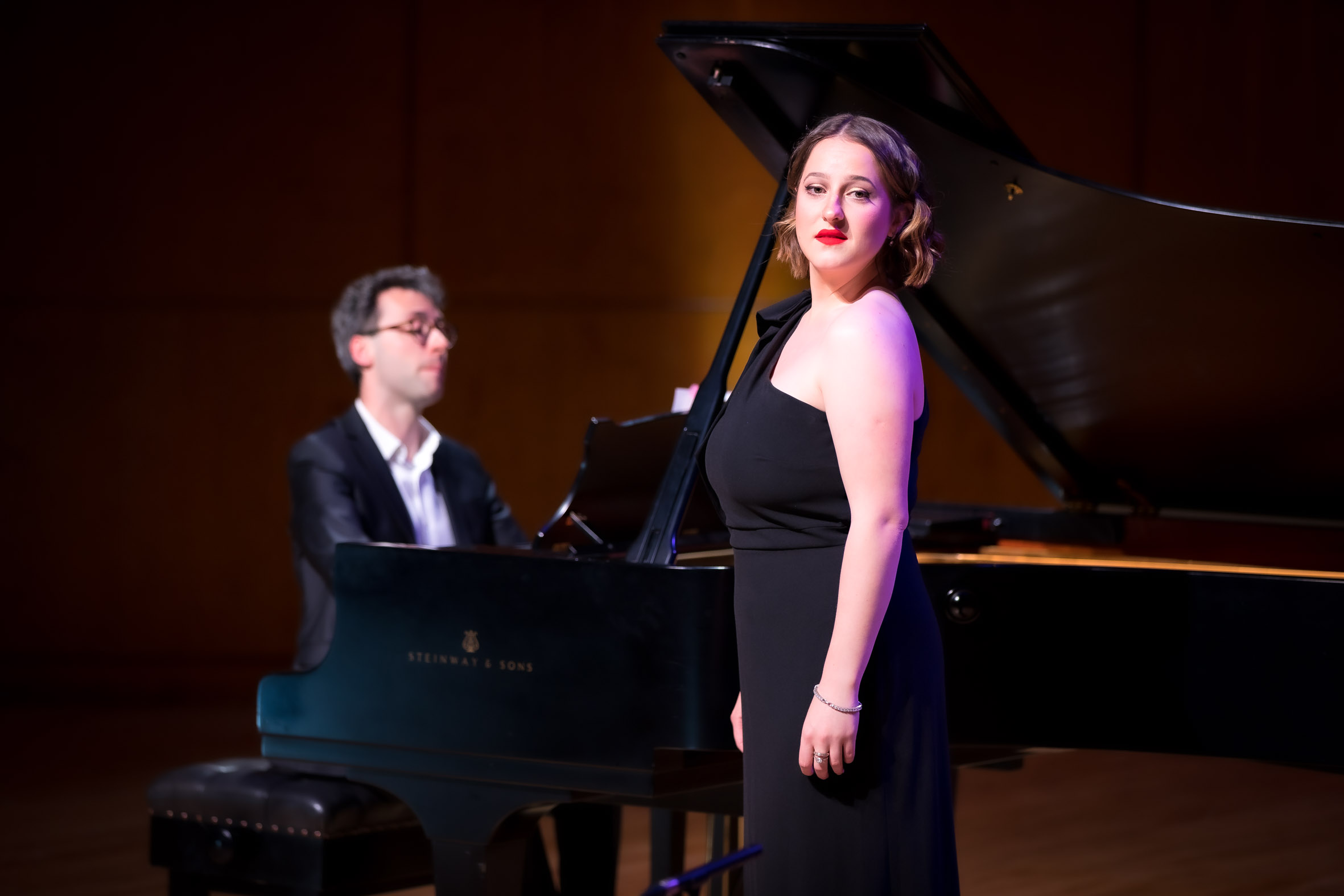 Women standing in front of piano and piano player